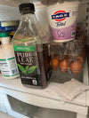 Bottle of Pure Leaf unsweetened tea, Fage yogurt, and eggs on a refrigerator shelf.
