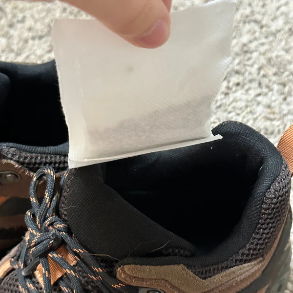 Person applying a white patch to the inside of a brown shoe